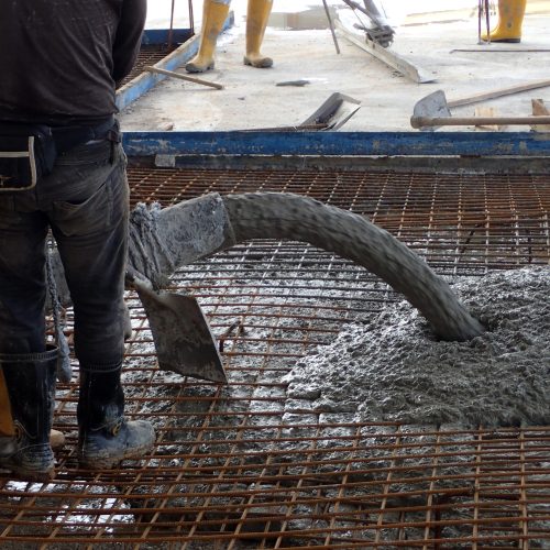 Construction worker pouring concrete for a building floor slab